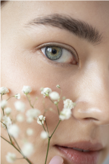 detail of a girl's eye with a flower resting on her face